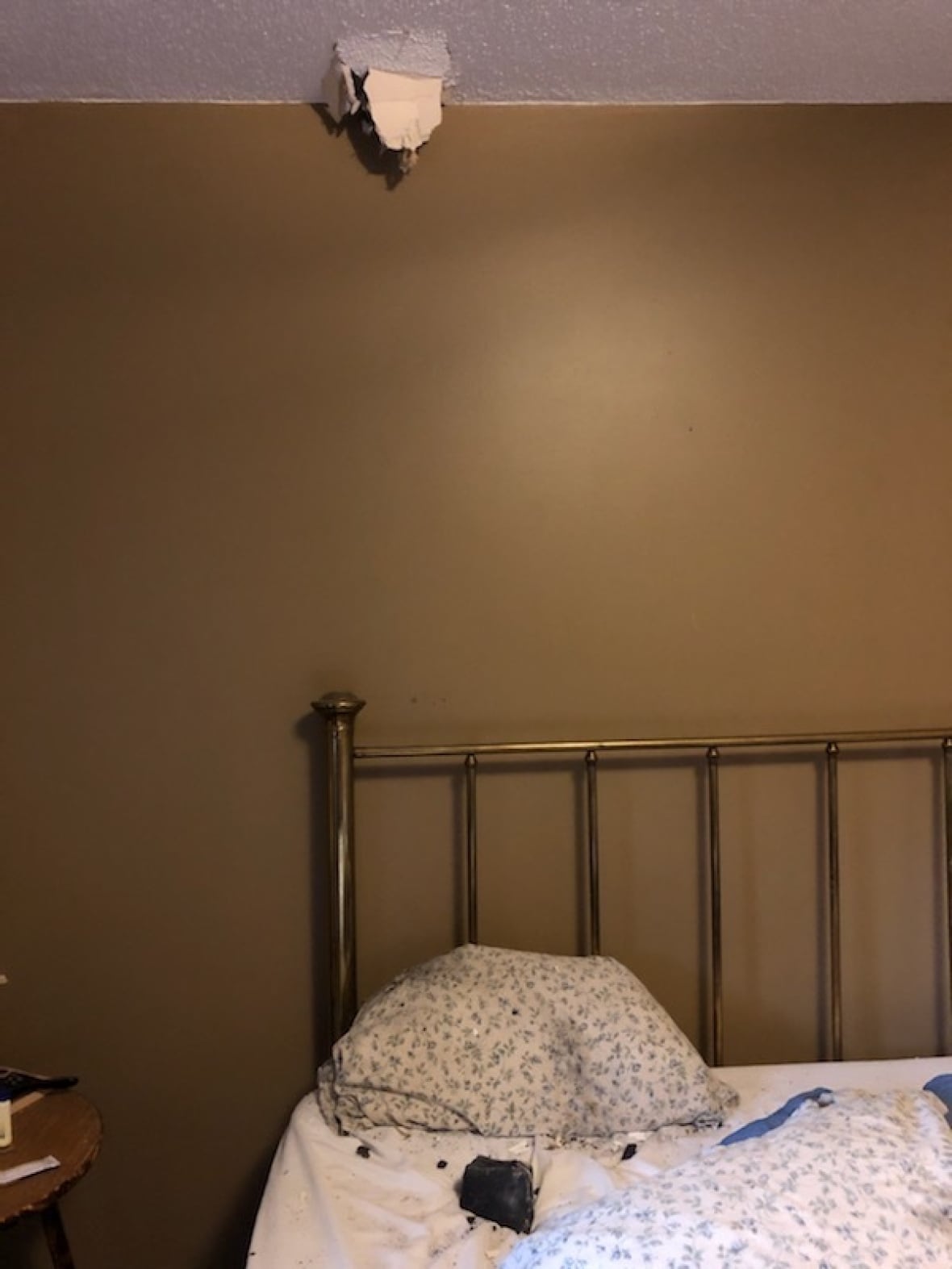 A hole in the ceiling is seen above a meteorite resting on a bed inside Hamilton's home. Hamilton said she was sound asleep when she was awakened by her dog barking, the sound of a crash through her ceiling and the feeling of debris on her face. (Submitted by Ruth Hamilton)