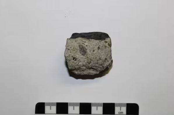 Figure 2- The main mass of the Nqweba meteorite showing the black fusion crust and brecciated interior (light grey) with broken mineral and rock fragments. Wits University